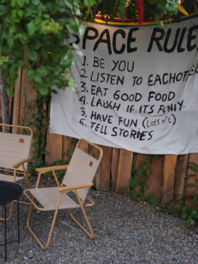 A hand-painted banner of house rules among climbing plants
