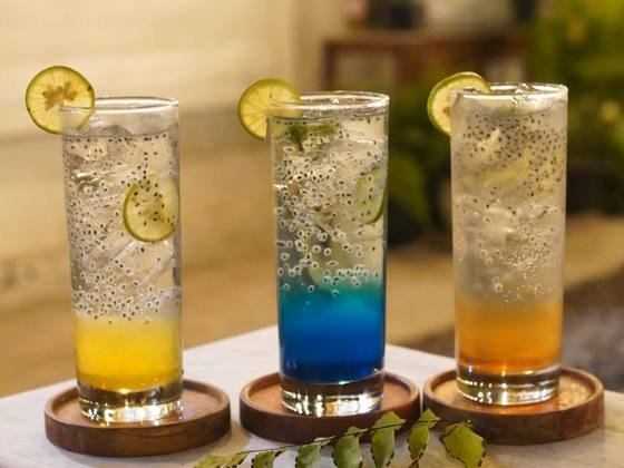 Three HAYY DAPOER sodas in yellow, blue and orange, served with lime slices
