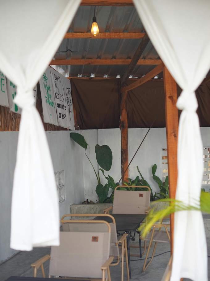 A lounge area with white curtains, a long table and plants