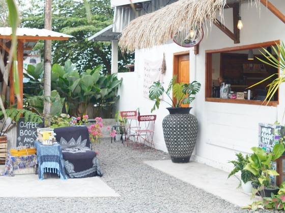 The HAYY DAPOER yard with gravel, lounge chairs, plants and a thatched bar